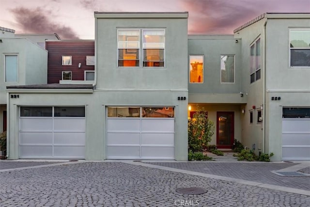 view of property featuring a garage, decorative driveway, and stucco siding