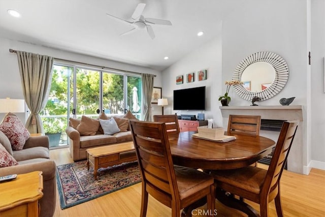 dining area featuring a ceiling fan, lofted ceiling, light wood-style flooring, a fireplace, and recessed lighting