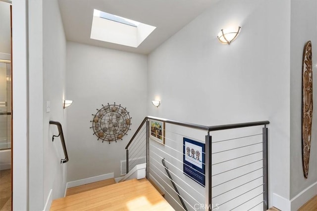 stairs featuring a skylight, baseboards, and wood finished floors