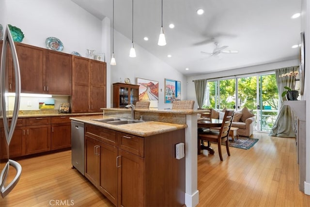 kitchen featuring sink, an island with sink, light hardwood / wood-style floors, decorative light fixtures, and high vaulted ceiling