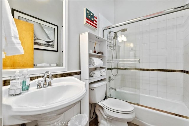 full bath with toilet, combined bath / shower with glass door, and a sink