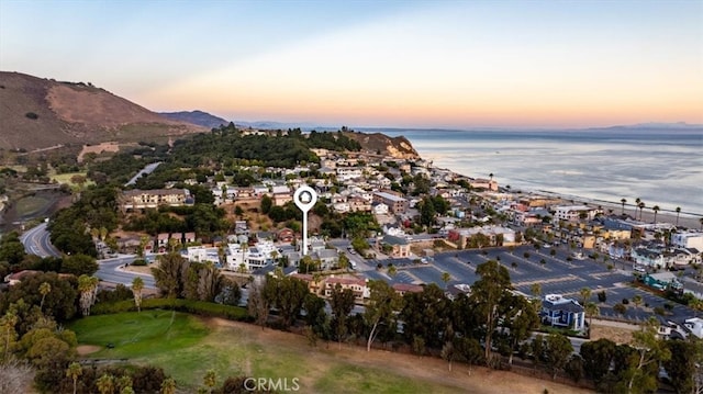 aerial view at dusk featuring a water and mountain view