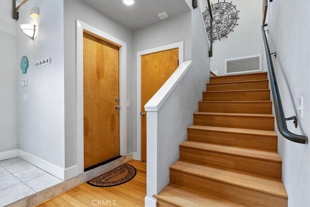 staircase with baseboards, visible vents, and wood finished floors