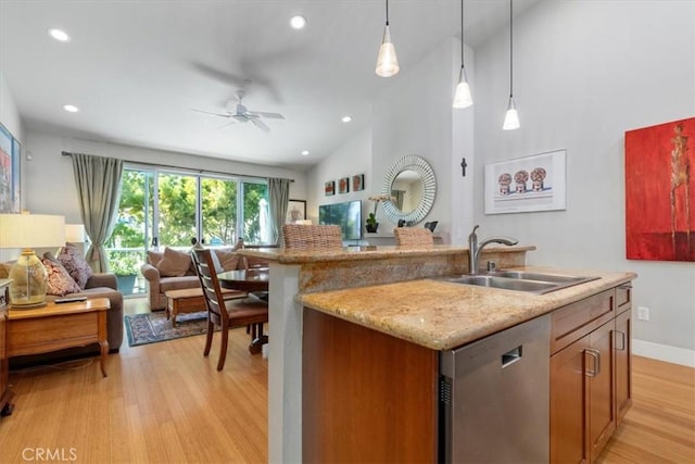 kitchen featuring dishwasher, open floor plan, a kitchen island with sink, pendant lighting, and a sink