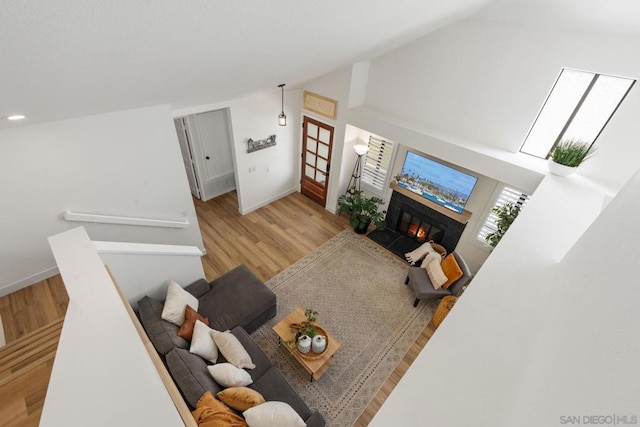 living room featuring a fireplace, light wood-type flooring, and vaulted ceiling