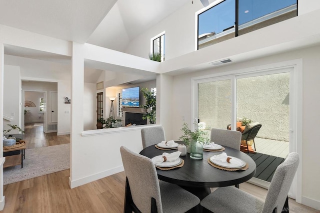 dining area with a high ceiling, light wood-type flooring, and plenty of natural light