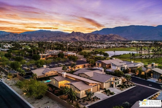 aerial view at dusk featuring a water and mountain view