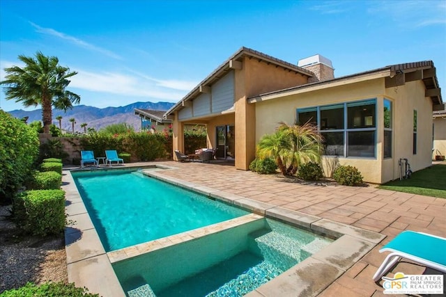 back of house with a fenced in pool, a patio area, and a mountain view