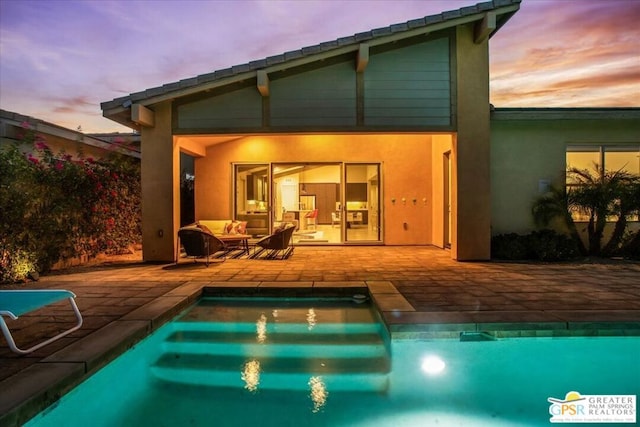 back house at dusk featuring outdoor lounge area and a patio area