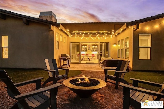 patio terrace at dusk featuring an outdoor fire pit