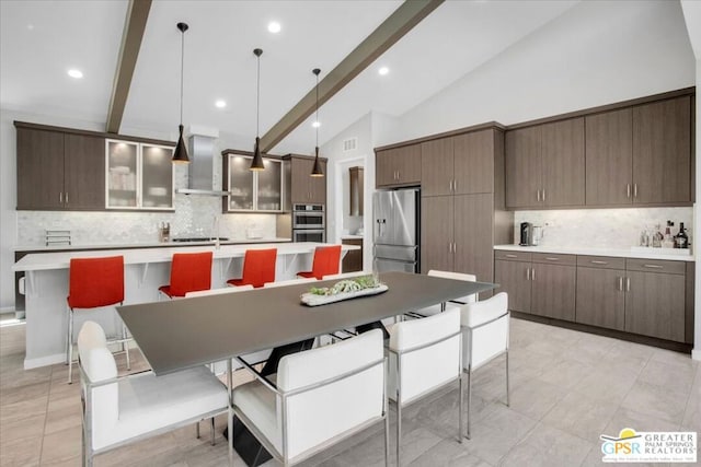 kitchen featuring appliances with stainless steel finishes, backsplash, beam ceiling, and wall chimney range hood