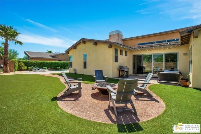 back of house featuring a lawn, a fire pit, and a patio