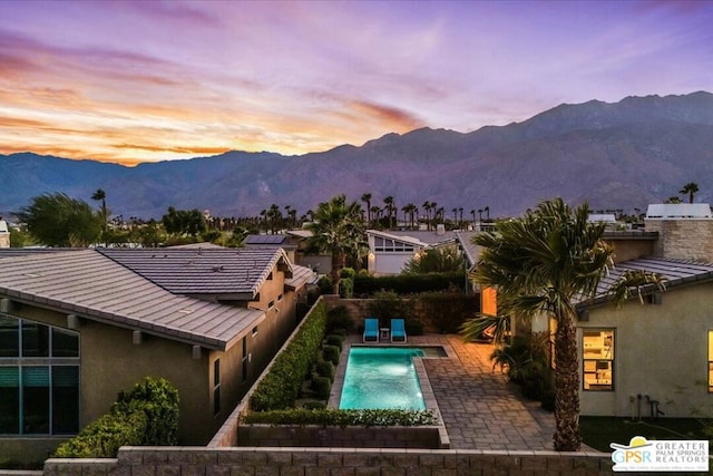 pool at dusk with a mountain view and a patio