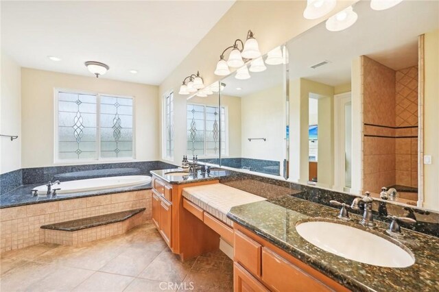 bathroom featuring tile patterned flooring, a relaxing tiled tub, and vanity