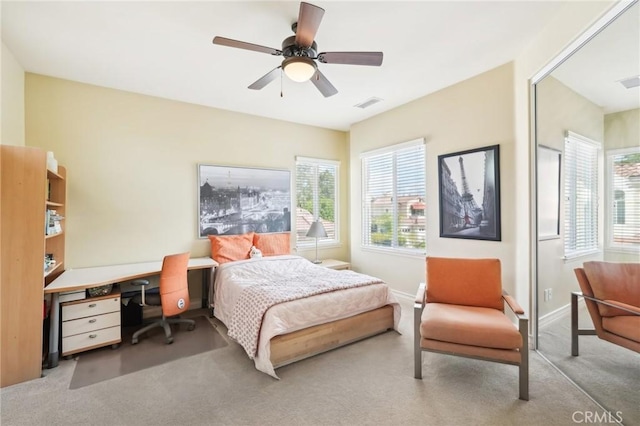 bedroom featuring ceiling fan, light carpet, and multiple windows