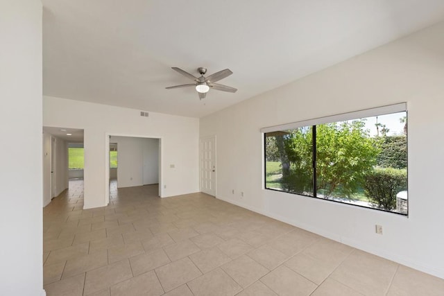 tiled empty room with ceiling fan and plenty of natural light