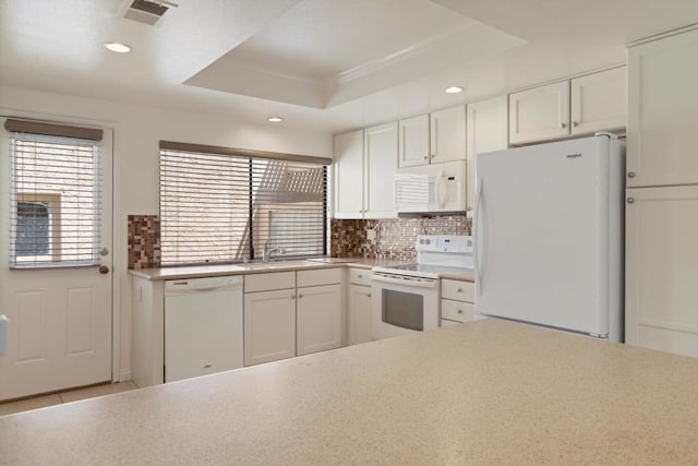 kitchen featuring backsplash, white appliances, a tray ceiling, sink, and white cabinetry