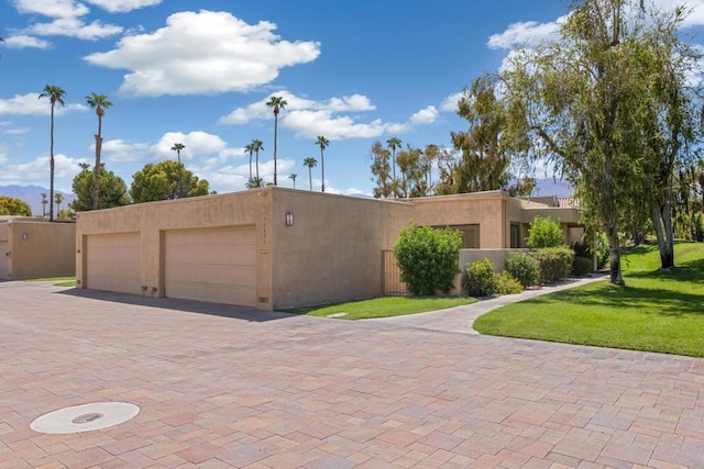 pueblo-style home with a front yard and a garage