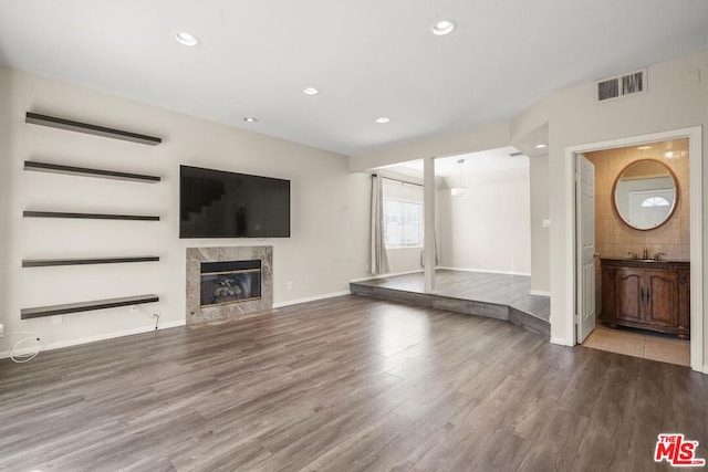 unfurnished living room with sink, light hardwood / wood-style flooring, and a premium fireplace