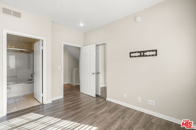 unfurnished bedroom with connected bathroom and hardwood / wood-style floors