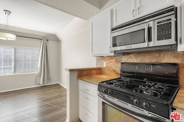 kitchen featuring black gas stove, white cabinetry, decorative backsplash, decorative light fixtures, and dark hardwood / wood-style flooring