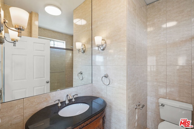 bathroom with tile walls, walk in shower, vanity, and toilet