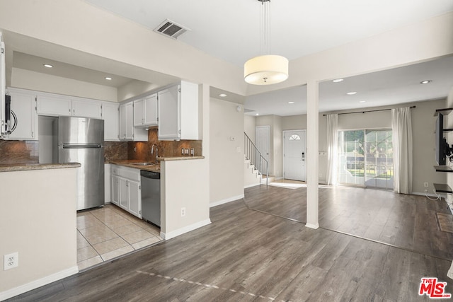 kitchen featuring appliances with stainless steel finishes, decorative backsplash, light hardwood / wood-style floors, white cabinets, and sink