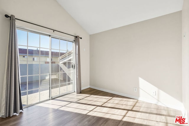 spare room with vaulted ceiling and hardwood / wood-style flooring