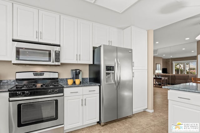 kitchen featuring dark stone countertops, appliances with stainless steel finishes, light tile patterned floors, and white cabinetry