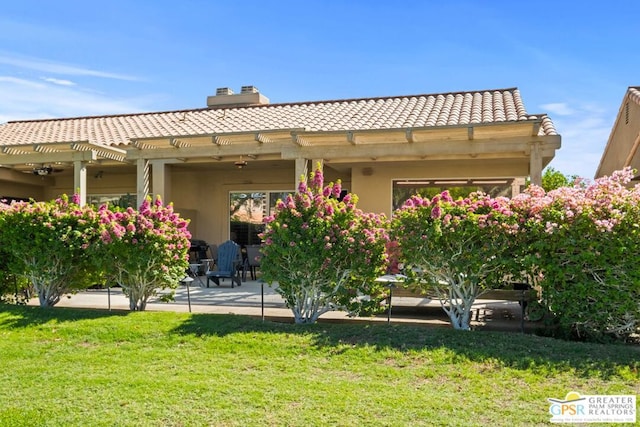 back of property with a lawn and a patio