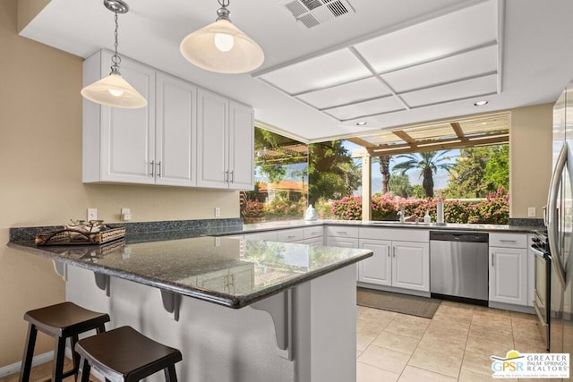 kitchen featuring pendant lighting, white cabinetry, dark stone counters, and stainless steel dishwasher