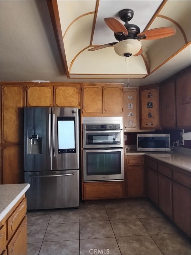 kitchen with dark tile patterned flooring, ceiling fan, appliances with stainless steel finishes, and vaulted ceiling