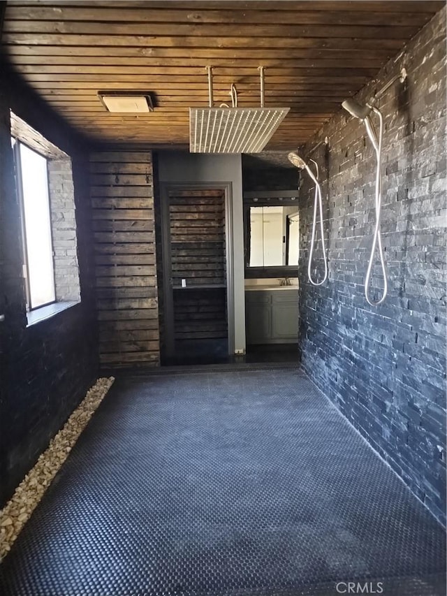 carpeted empty room with brick wall and wood ceiling