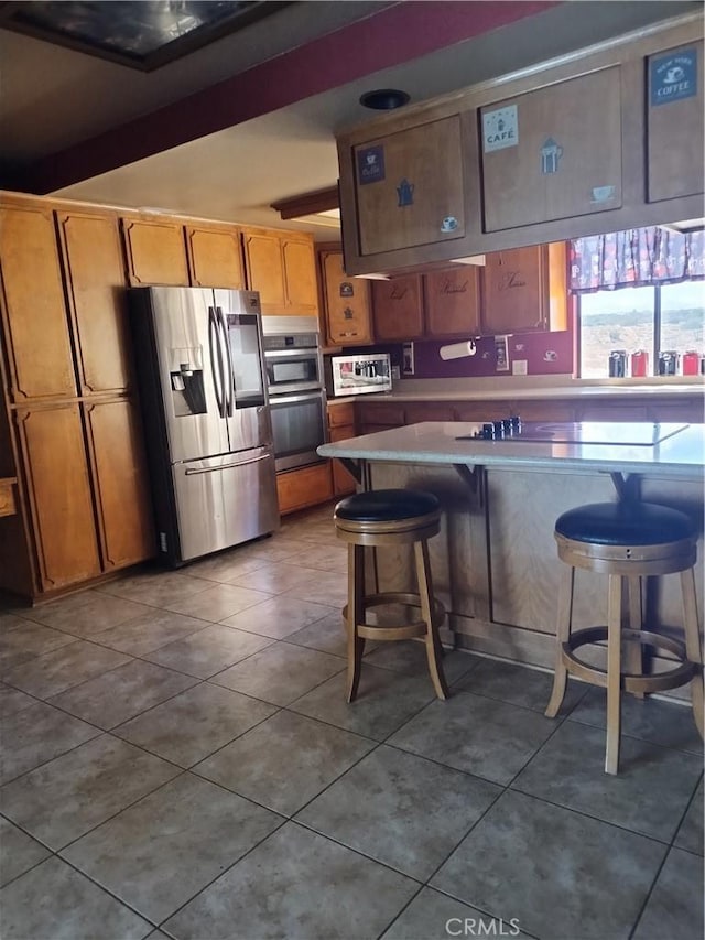 kitchen featuring a kitchen bar, stainless steel refrigerator with ice dispenser, kitchen peninsula, tile patterned floors, and beamed ceiling