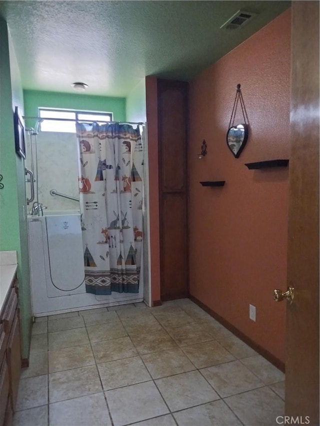 bathroom with tile patterned flooring, a textured ceiling, and vanity