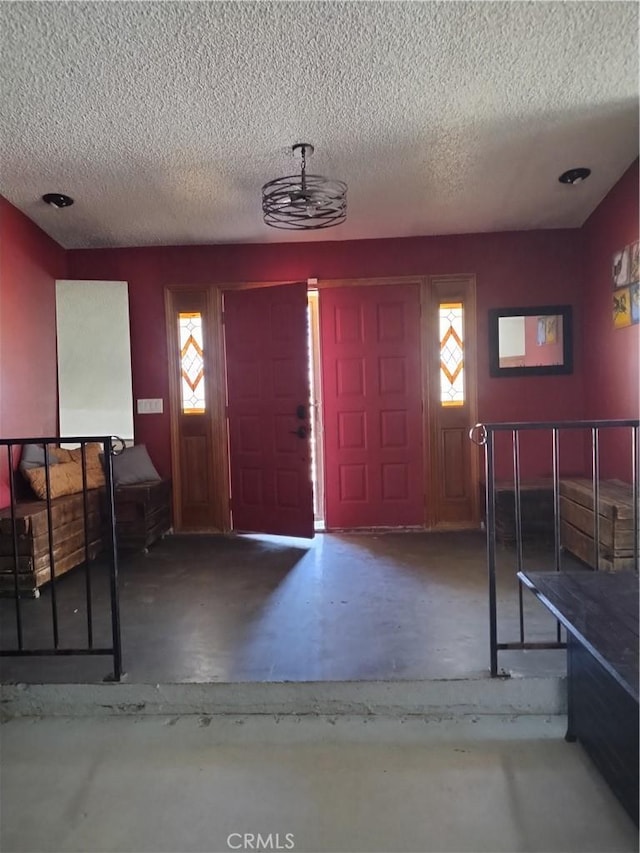 foyer with a textured ceiling, a wealth of natural light, and concrete floors