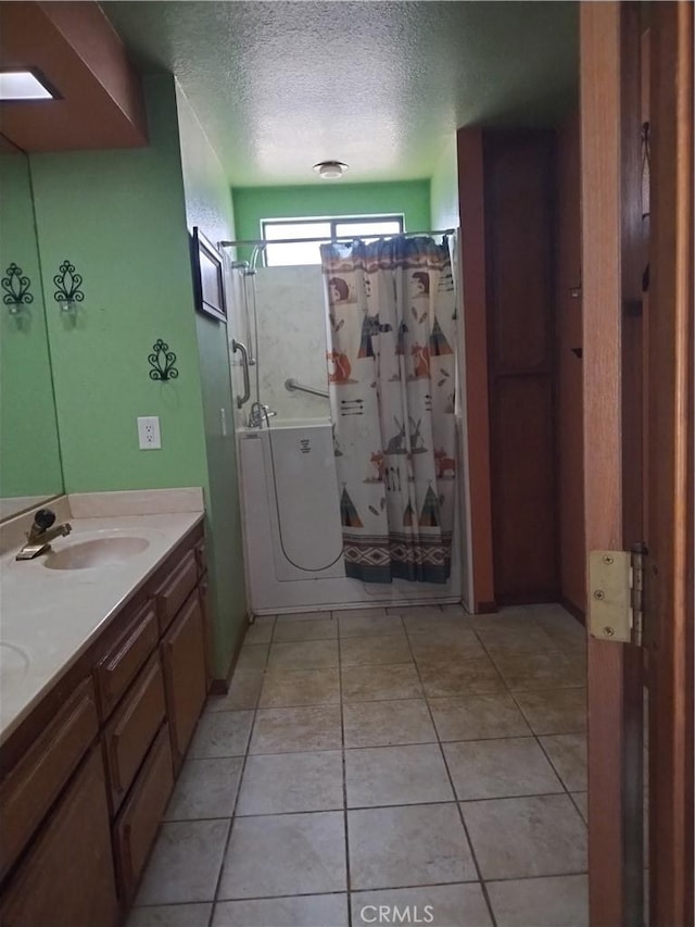 bathroom with vanity, a textured ceiling, tile patterned floors, and walk in shower