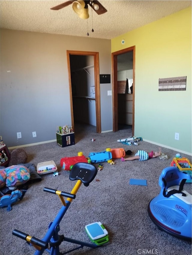 recreation room featuring ceiling fan, carpet, and a textured ceiling