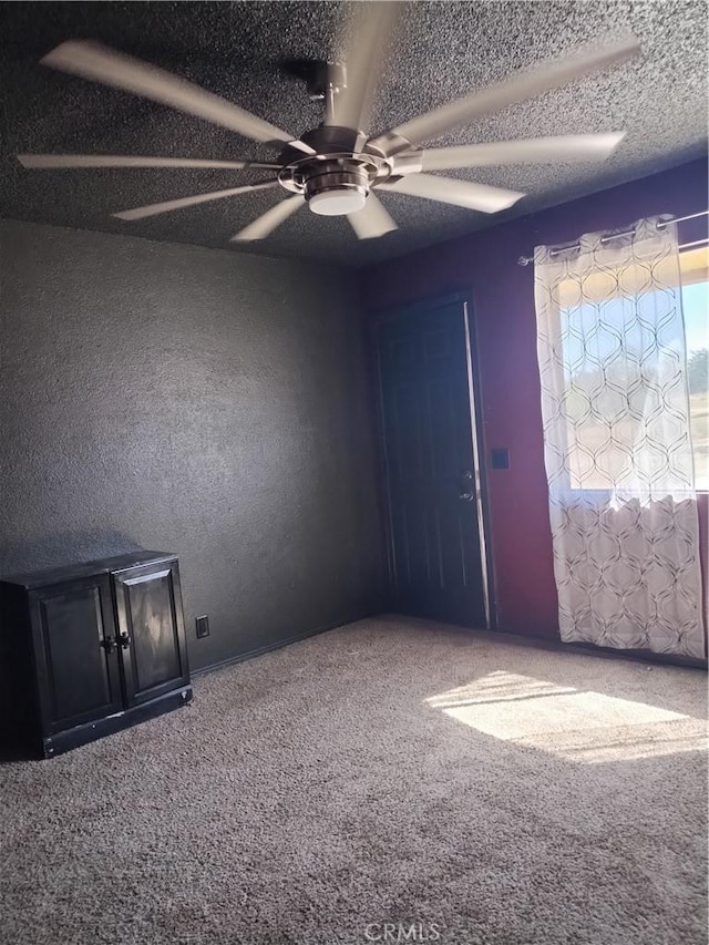 unfurnished room with ceiling fan, carpet floors, and a textured ceiling