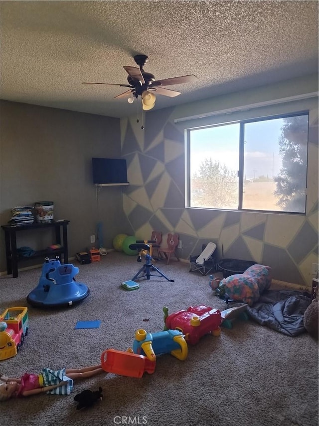 recreation room with carpet flooring, a textured ceiling, and ceiling fan