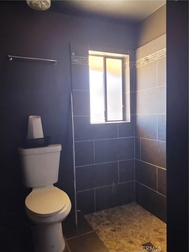 bathroom with tiled shower and toilet