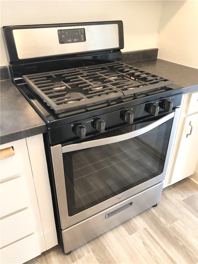 interior details featuring light hardwood / wood-style flooring, white cabinets, and stainless steel range with gas stovetop