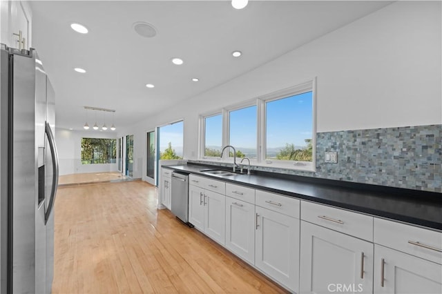 kitchen with sink, white cabinetry, hanging light fixtures, light wood-type flooring, and stainless steel appliances