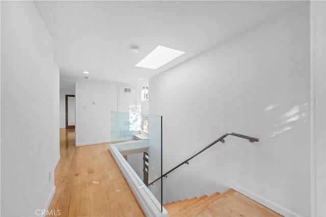 staircase with a skylight, baseboards, and wood-type flooring