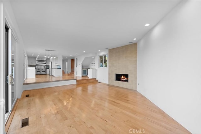 unfurnished living room with recessed lighting, light wood-style floors, visible vents, and a large fireplace