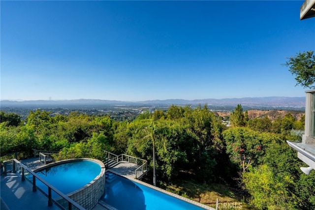 view of pool featuring a view of trees, a mountain view, and a pool with connected hot tub