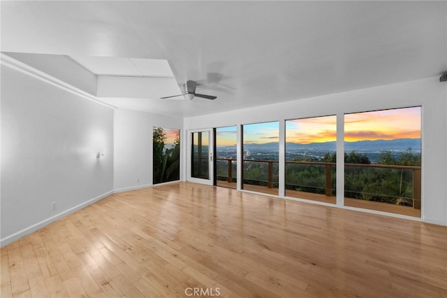 spare room featuring baseboards, wood finished floors, and a ceiling fan