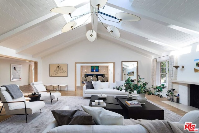 living room featuring vaulted ceiling with beams and light hardwood / wood-style flooring