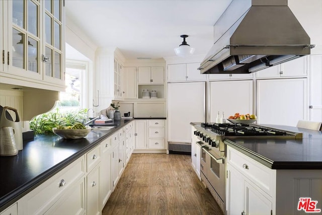 kitchen with range with two ovens, white cabinetry, wood-type flooring, and exhaust hood