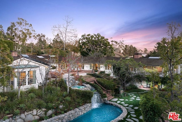 pool at dusk featuring a patio area and pool water feature